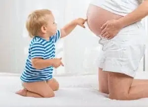 Little cute boy looking at his mother pregnant tummy
