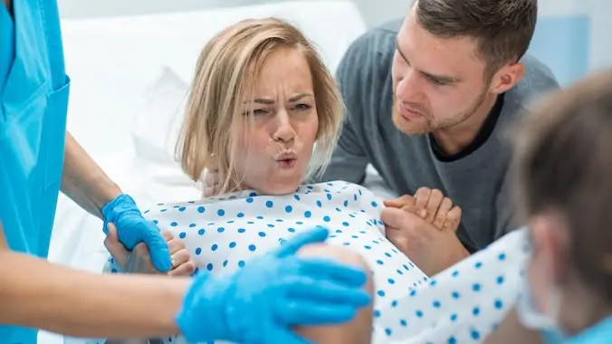 Husband Holds Her Hand for Support While in Labor in the Hospital