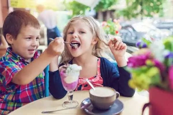 Little bro and sis eating ice cream at an outdoor cafe in outdoor cafe