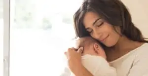 Pretty woman holding a newborn in her arms