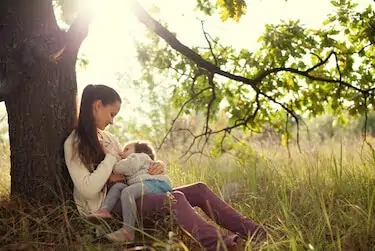 Young mother feeding toddler outdoors