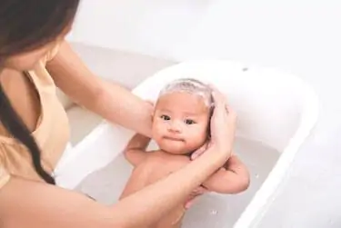 A baby is being bathed by his mother