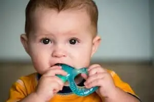 Baby chewing on teething ring toy
