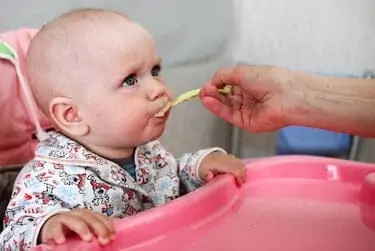 Beautiful baby eats porridge from mom's hand