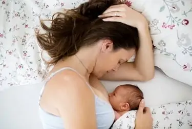 Mom breastfeeds her newborn in side-lying position