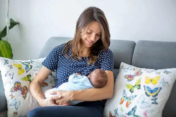 Young mother breastfeeding her newborn baby boy at home