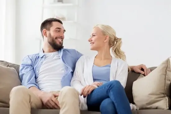 husband and wife sitting on sofa smiling