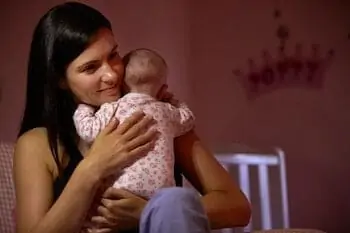 Mother At Home Cuddling Newborn Baby 