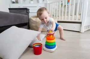 Baby crawling on floor at living room and reaching for toy tower