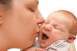 Mother Kissing Yawning Newborn