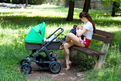 mom breastfeeds her son in a park