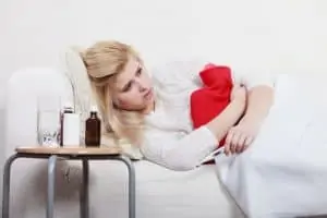 Woman having stomach cramps lying on sofa