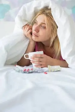 Young woman with coffee mug and medicines