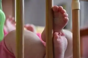 Baby feet sticking out through the rails of a crib