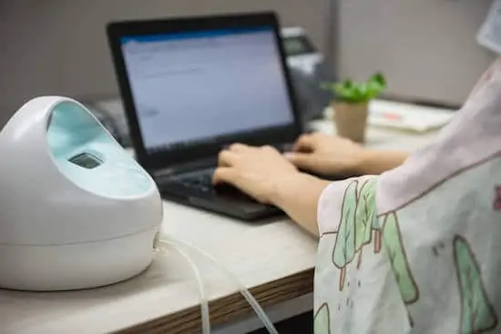 Mother pumping breastmilk by Automatic breast pump machine at work place