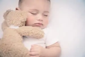 adorable infant sleeping with little bear