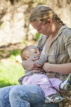 Mother breastfeeds baby in park
