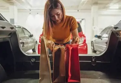 young mom keeping shopping bags in the car