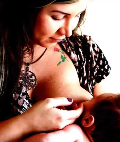 Mother touching baby as she breastfeeds her