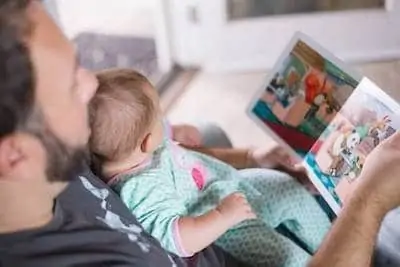 dad carrying baby and reading book