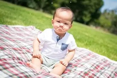 baby sits on plaid pad