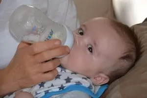 baby looking at camera while bottle-feeding 