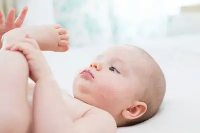 Cute baby girl lying and pulling leg into her mouth