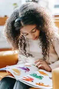 Child studying colorful pictures in book
