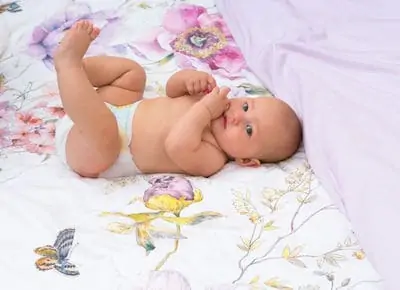 Baby lies on bed and kicking her legs