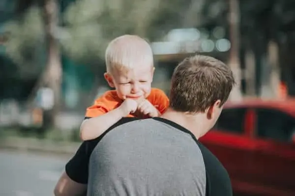 father carries crying child