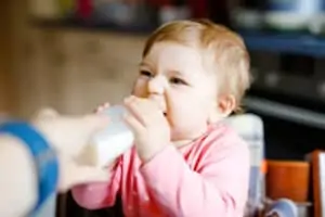 baby holds bottle and drinks milk