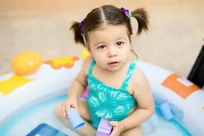 Little girl playing with water in an inflatable pool