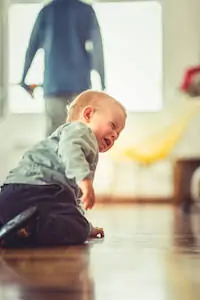 Toddler boy is sitting alone on the floor and crying