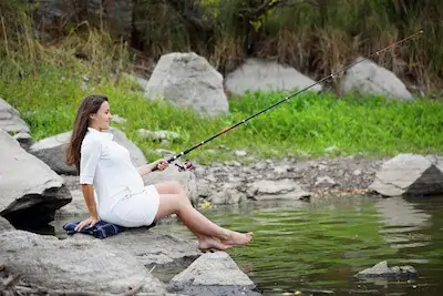 pregnant woman fishing on the river bank