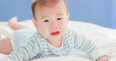 baby lying on bed and cry