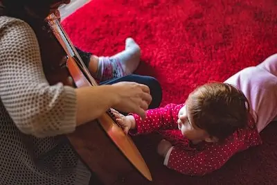 mom spends time with toddler by playing a guitar