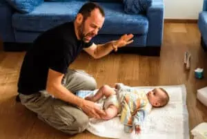 father changes baby diaper