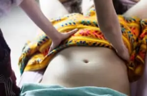 Postpartum doula gives a manual abdominal massage
