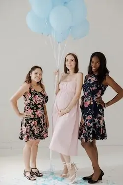 group of friends and pregnant woman holding ballon 
