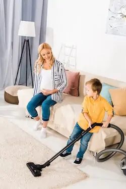 toddler helps pregnant mom in vacuuming