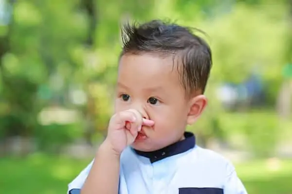 Asian little boy rubs her nose