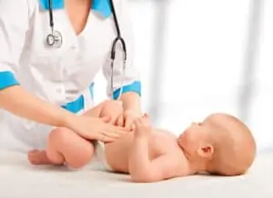 Doctor examines, massaging baby tummy