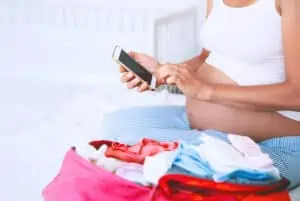 woman in pregnancy looking at phone making a list