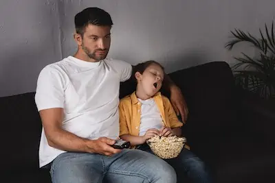 dad with yawning son on sofa