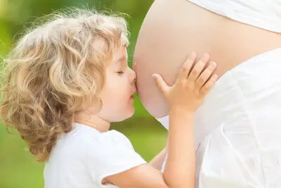 kid touching mom's pregnant belly