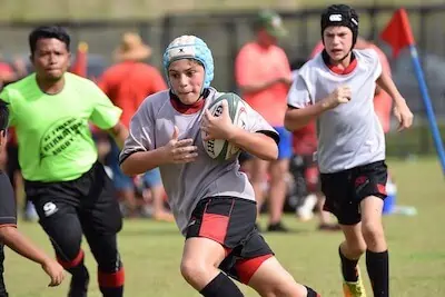 kid runs fast with a rugby ball in hand