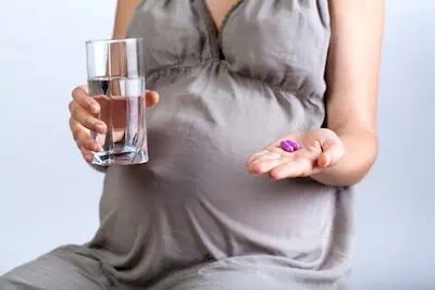 pregnant woman with medicine and glass of water in hand