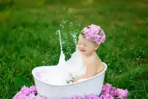 baby enjoys milk bath on a tub