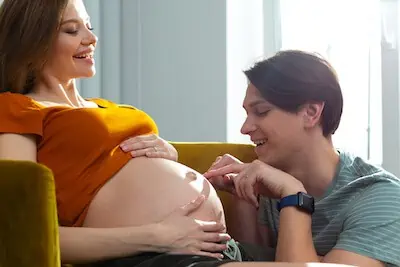 husband touches pregnant wife's belly button