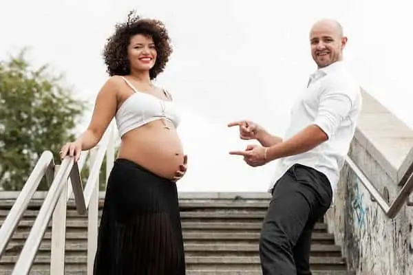 husband points to pregnant wife on stairs